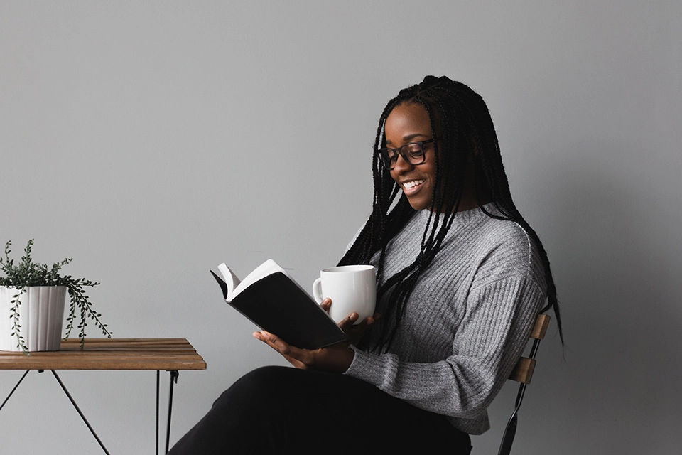 Woman reading a book with a white mug