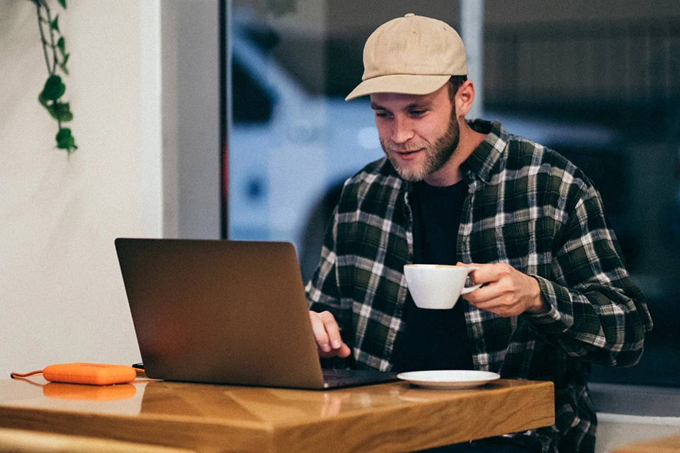 influencer drinking a cup of coffee and looking at a laptop